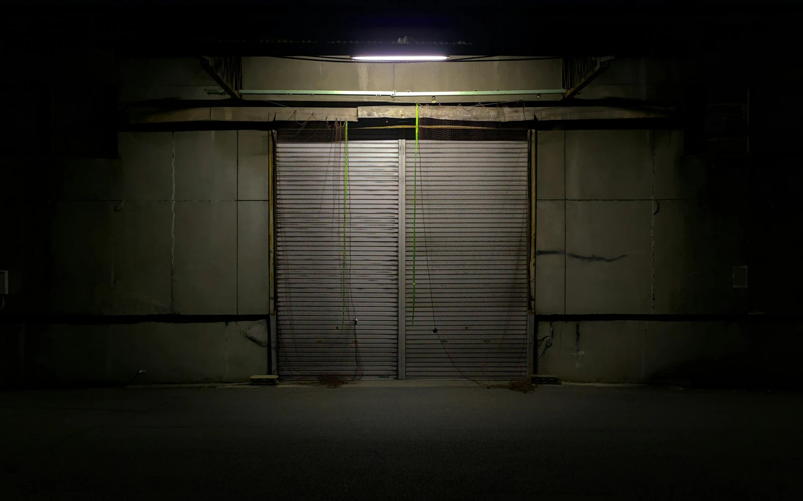 Le rideau métallique d'un commerce, baissé sous une applique, la nuit