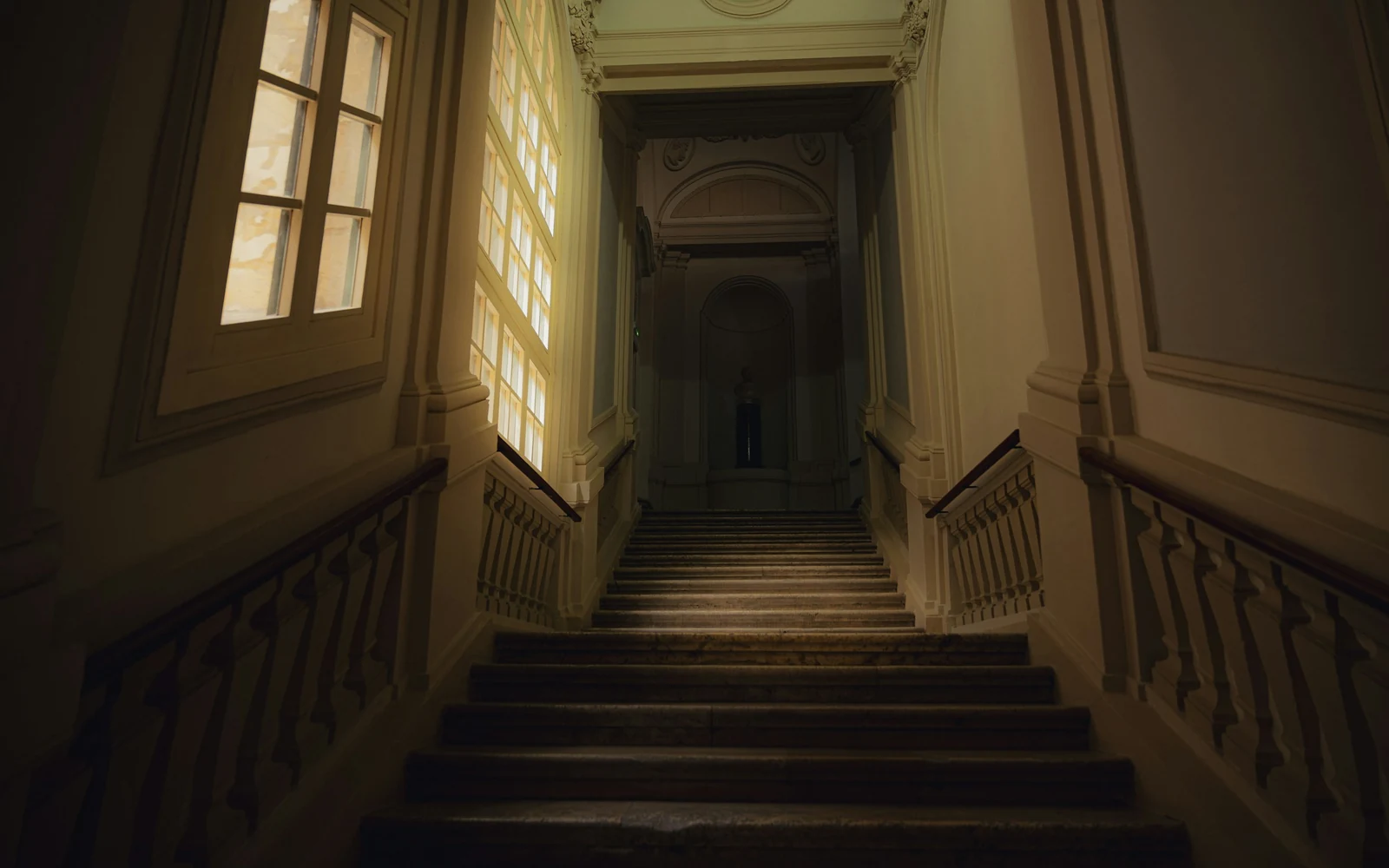 La cage d'escalier d'un immeuble ancien, éclairée par la lumière d'une fenêtre