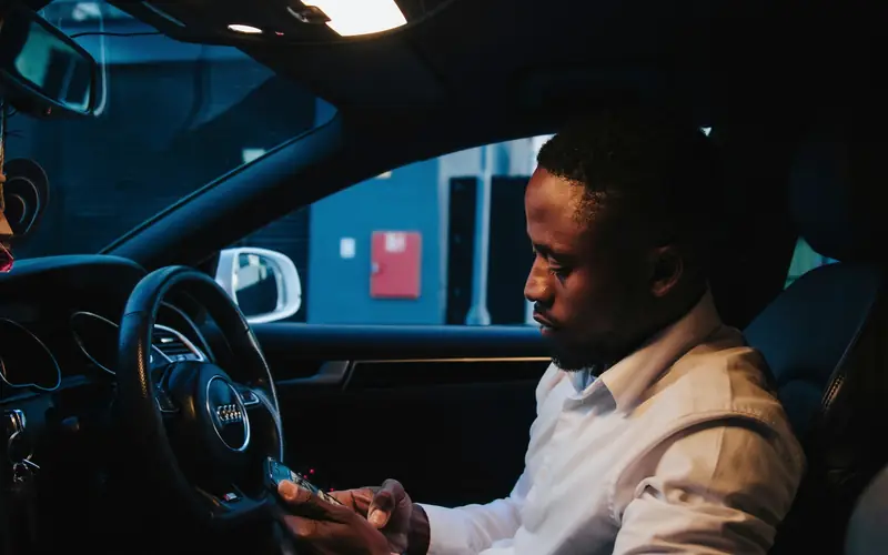 Un indépendant seul dans sa voiture le soir, qui regarde les appels manqués sur son téléphone