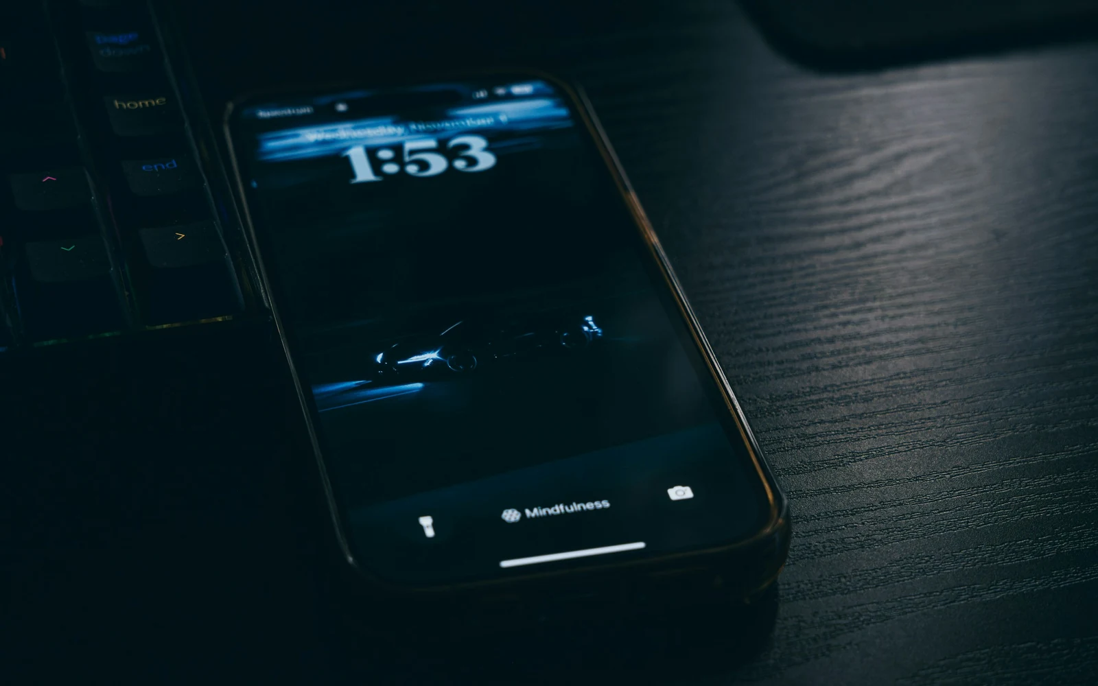 Un smartphone écran allumé, posé sur un plan de travail sombre