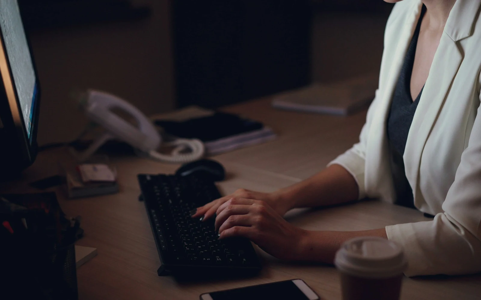 Un poste de travail éclairé d'une lampe, clavier et téléphone de bureau, en soirée