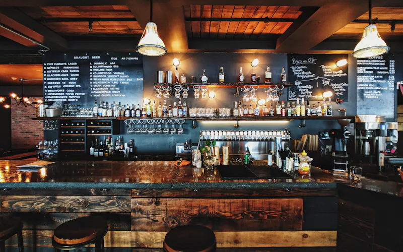 Salle de restaurant le soir, comptoir en bois et lumières chaudes
